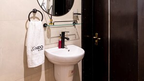 Een badkamer met een wit wastafelmeubel, een spiegel, een handdoekrek en een zwarte deur.