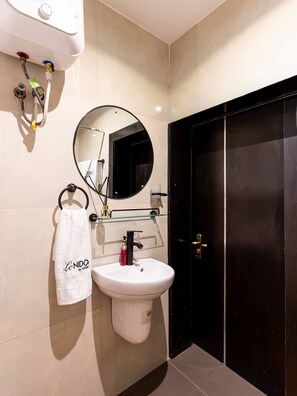 Een badkamer met een wit wastafelmeubel, een spiegel, een handdoekrek en een zwarte deur.