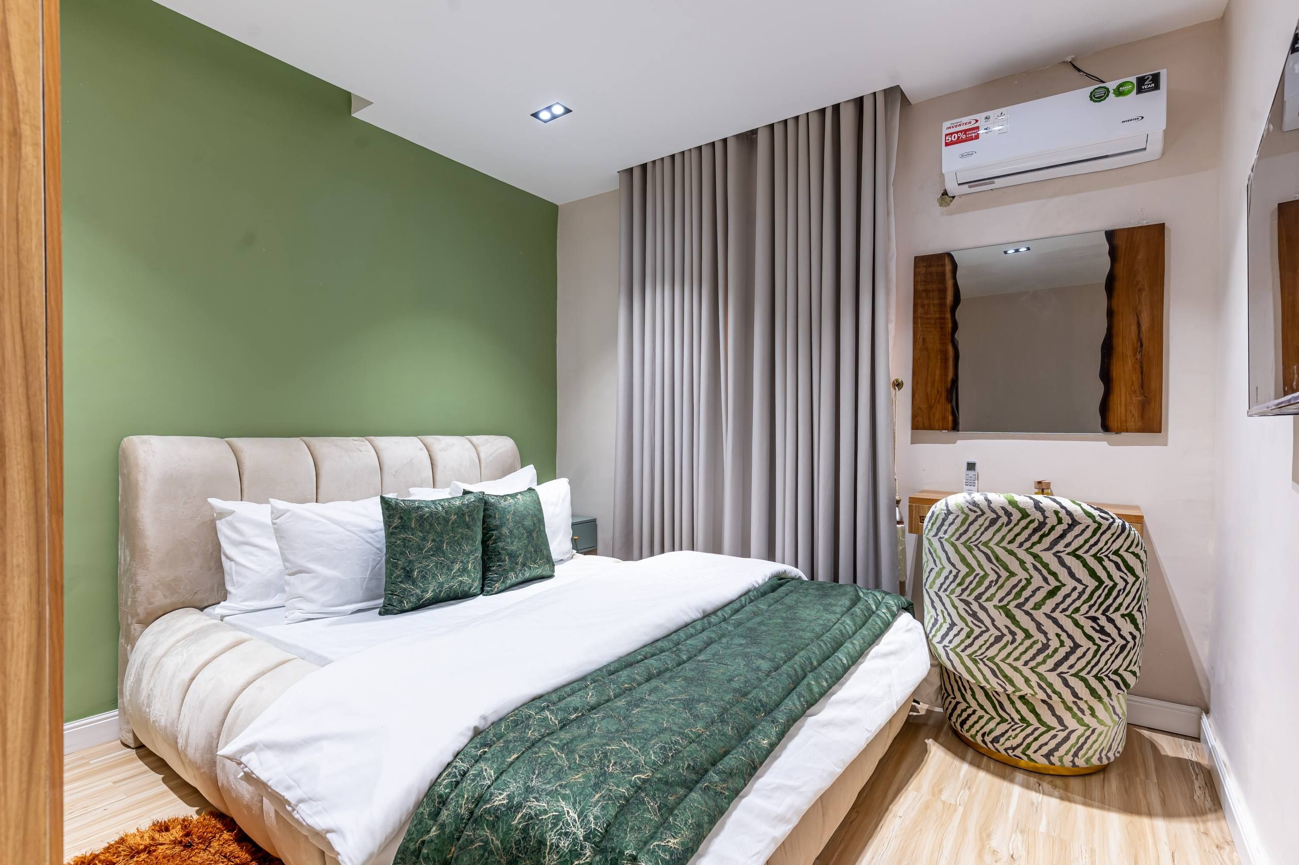 A modern bedroom with a bed, a bedside table, a mirror, and an air conditioning unit.