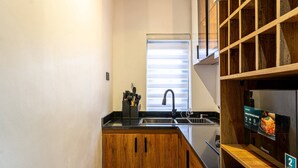 Een kleine keuken met houten kastjes, een roestvrijstalen spoelbak en een ingebouwde oven.