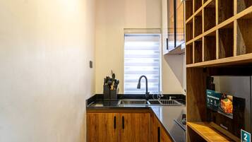 Cocina compacta con armarios de madera, pileta de acero inoxidable y horno empotrado.