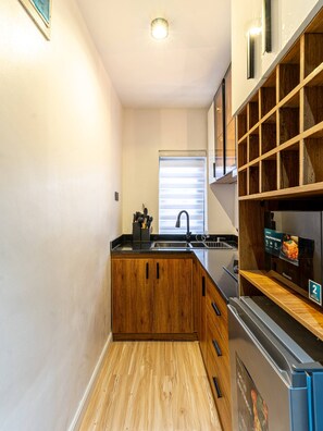 Een kleine keuken met houten kastjes, een roestvrijstalen spoelbak en een ingebouwde oven.