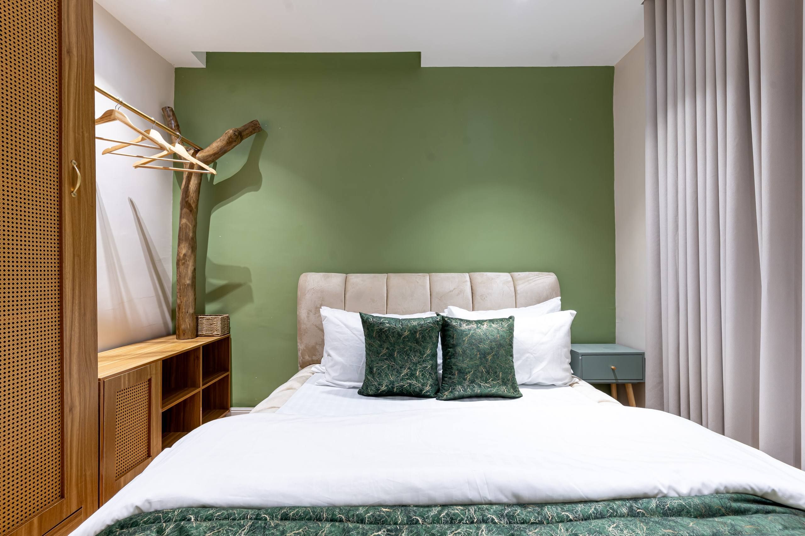 Un dormitorio con cama, mesita de noche, cómoda y lámpara de pared.