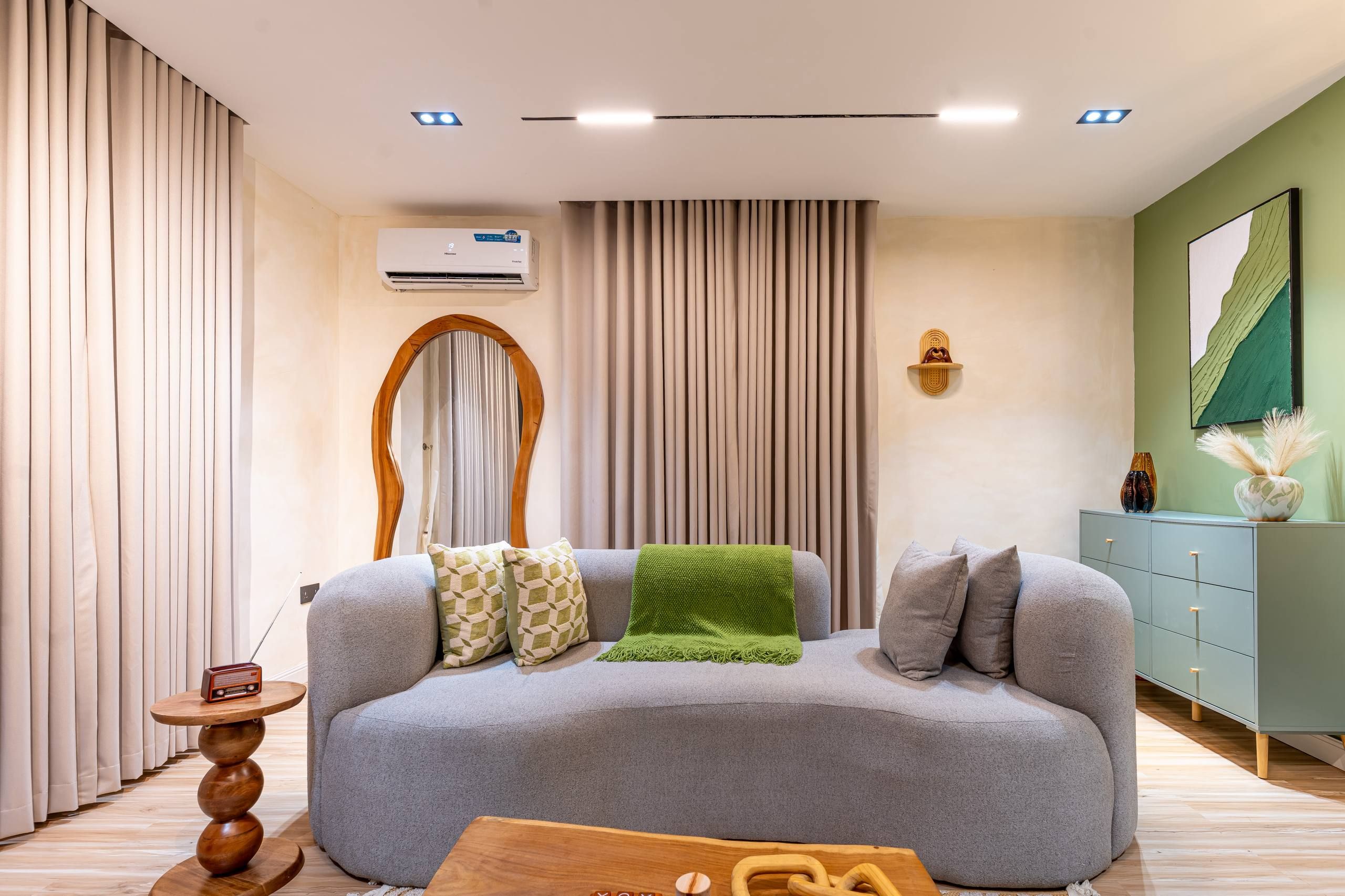 Una sala moderna con un sofá gris, una mesa de centro de madera y una manta verde.