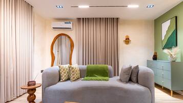 Una sala moderna con un sofá gris, una mesa de centro de madera y una manta verde.
