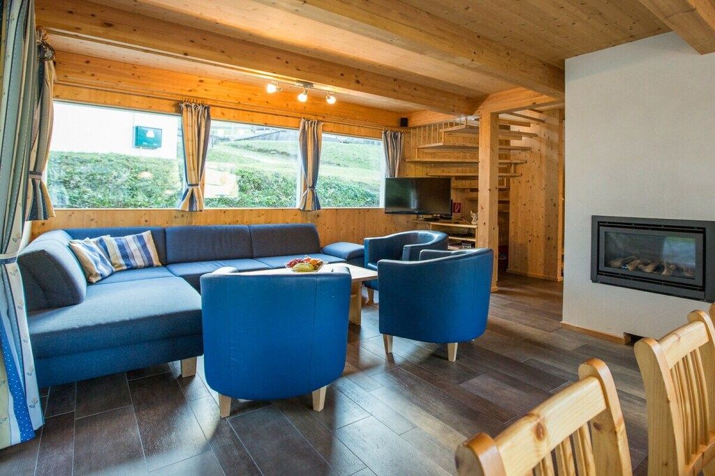 Een gezellige zithoek met een bank, stoelen, een open haard en een televisie.