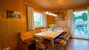 Puisesti sisustettu tila, jossa on ruokapöytä, tuoleja, penkki ja ikkuna, jossa on verhot.