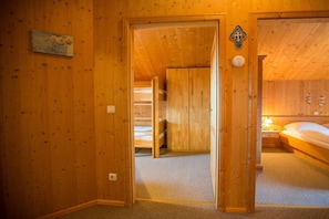 A wooden interior with a bed, a nightstand, and a door leading to another room. - Cabin in Annaberg with swimming pool (Annaberg)