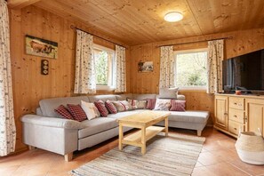 L’intérieur d’un chalet accueillant, avec un canapé, une table basse en bois et un téléviseur.
