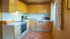 Cocina compacta con armarios de madera, horno integrado, microondas y pileta.