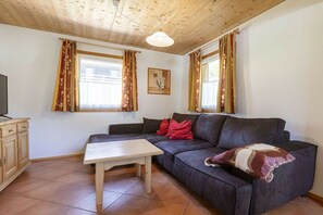 Ein Wohnzimmer mit einer Couch, einem Couchtisch und einem Fernseher auf einer Kommode.