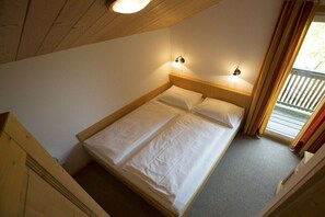 Ein Einzelbett mit Holz Kopfteil, zwei Nachttischlampen und ein Fenster mit Vorhängen.
