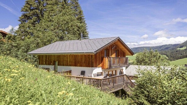 A wooden chalet with a balcony, surrounded by greenery and mountains. - Cabin in Annaberg with swimming pool (Annaberg)