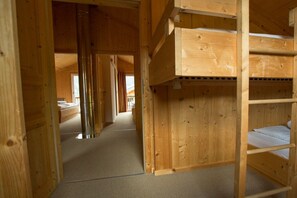 Un intérieur en bois avec un lit superposé et un couloir menant à une autre pièce.