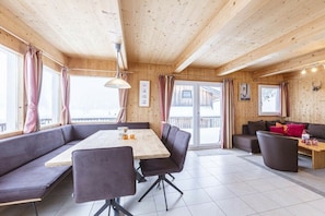 Ein Holzinterieur mit Essbereich, Sofa und Blick durch die Glastür.