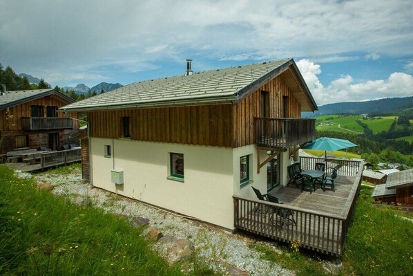 Eine Chalet mit Balkon, einer Terrasse und Blick auf eine Berglandschaft.