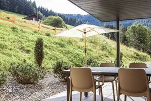 An outdoor patio with a table and chairs, a wooden fence, and a view of a hillside. - Holiday apartment for 6 people & infinity pool (St. Martin am Tennengebirge)