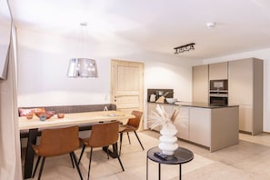Una cucina moderna con isola centrale, zona pranzo con una panca e una lampada a sospensione.
