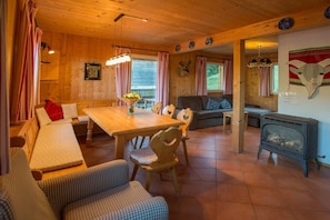 Een gezellig chaletinterieur met een houten eettafel, een bank, een open haard en een opbergplaats gemonteerd hert.