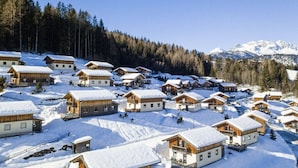 A snow-covered village with wooden cabins and a mountain backdrop. - Cabin in Annaberg with swimming pool (Annaberg)