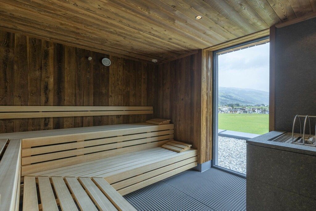 Eine Sauna mit Holzbänken und einem großen Fenster mit Blick ins Freie.