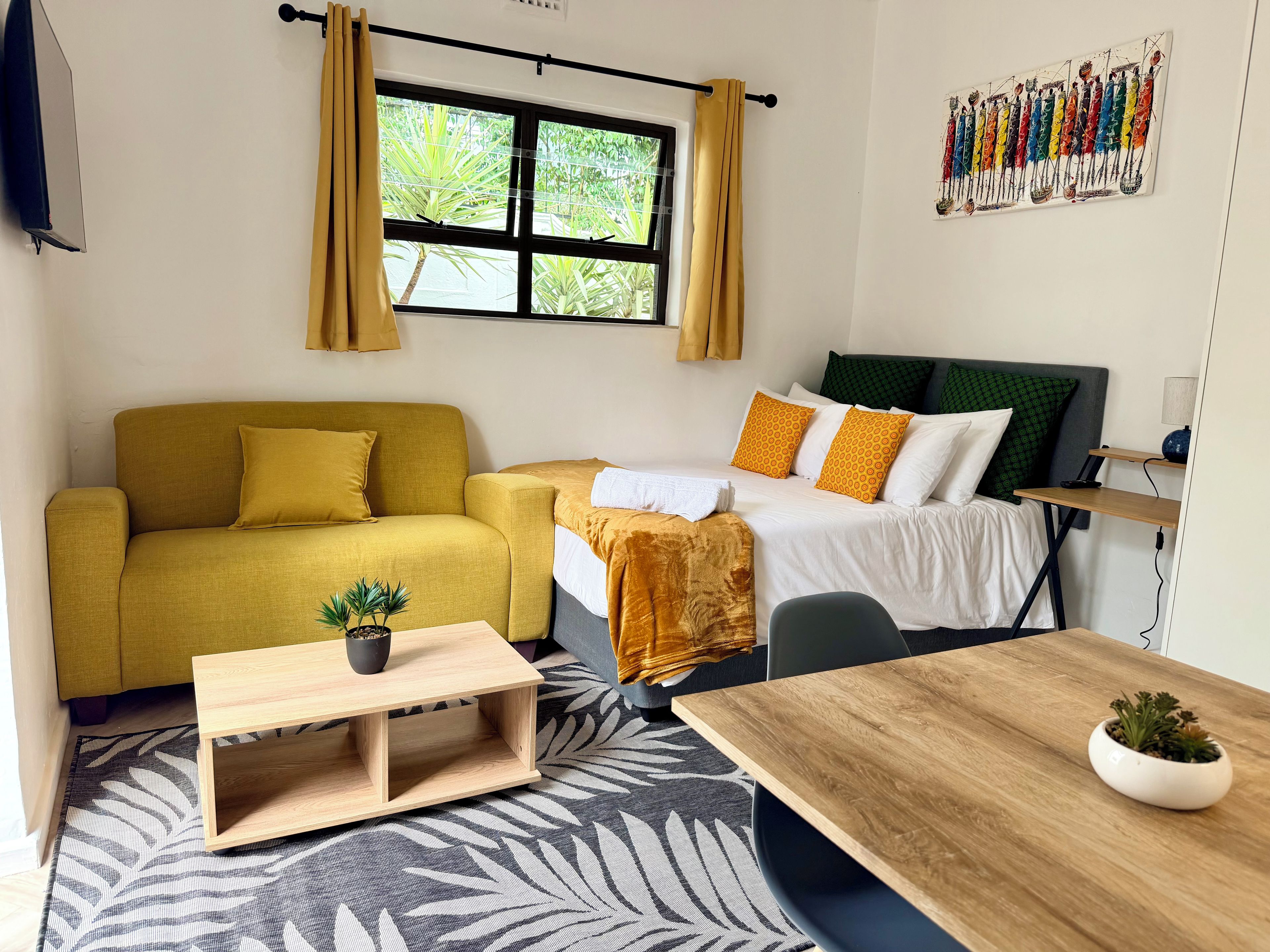 A room with a sofa, a bed, a table, and a window with curtains.