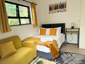 Ein Hotelzimmer mit Bett, Sofa, Schreibtisch und einem Fenster mit Vorhängen.