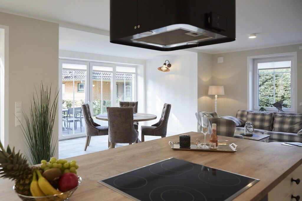 Cocina moderna con placa de inducción, comedor con sillas y sala de estar con sofá.