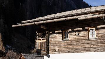 Une cabane en bois rustique, dotée d’un toit à forte pente, d’une fenêtre et d’une cheminée.