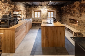 A rustic kitchen with a central island, wooden cabinetry, and stone walls. - historic Chalet Raneburg (Matrei in Osttirol)