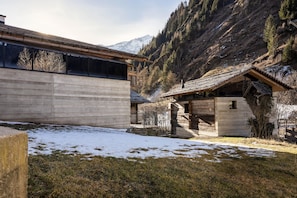 A traditional wooden chalet with a stone foundation, surrounded by a snowy landscape and mountains in the background. - historic Chalet Raneburg (Matrei in Osttirol)
