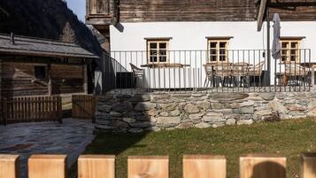 Ein rustikales Gebäude mit Steinmauer, Holzzaun und einer Sitzgelegenheit im Freien.
