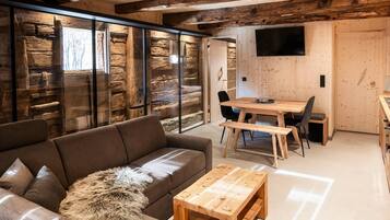 Un interior moderno con una mesa de comedor de madera, un sofá y un televisor montado en la pared.