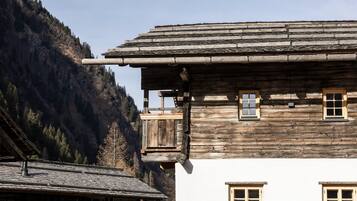 Ein traditionelles Holzhaus mit geneigtem Dach, einem Balkon und mehreren Fenstern.