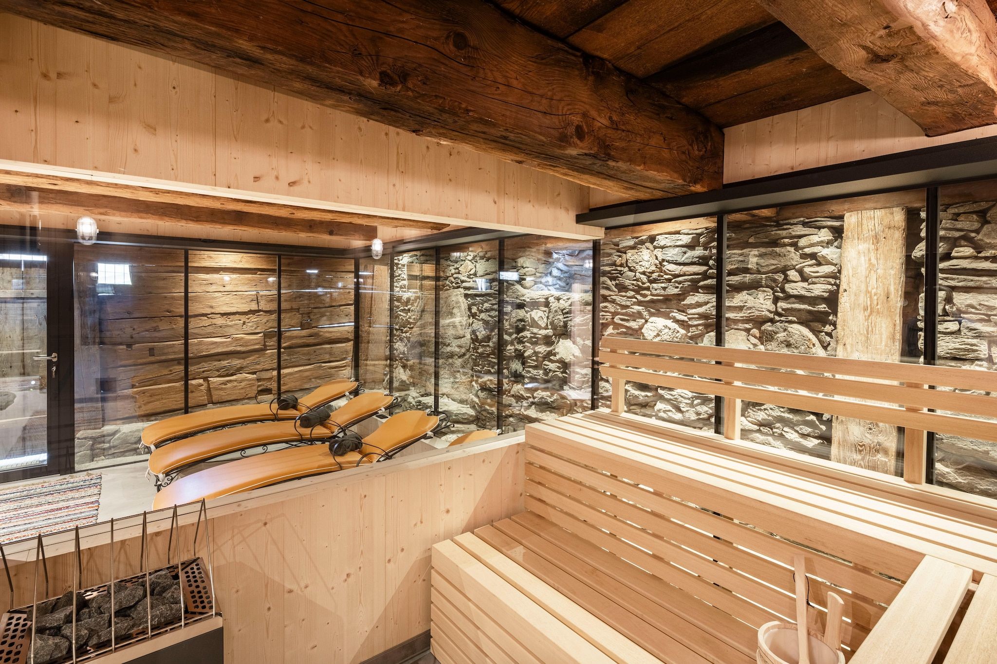 Un sauna avec des bancs en bois et un mur en pierre en arrière-plan.