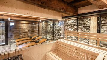 Un sauna avec des bancs en bois et un mur en pierre en arrière-plan.