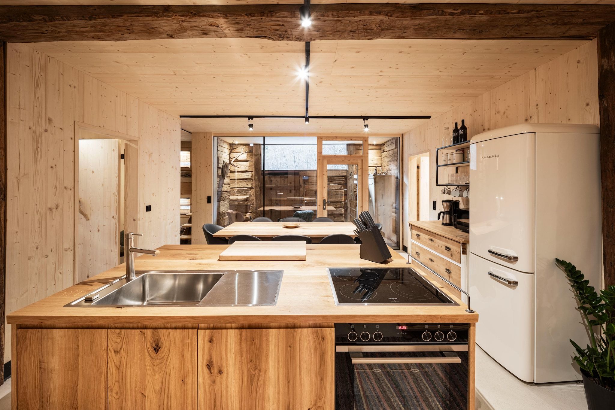 Una cocina moderna con armarios de madera, una isla central con pileta y estufa, y un refrigerador.