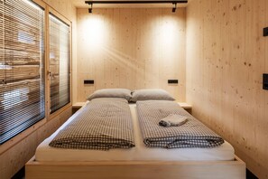 A wooden room with a bed, two bedside tables, and a window with blinds. - Charming chalet-style feeder house (Matrei in Osttirol)