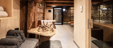 Un cuarto de spa con paredes de madera, un banco de piedra y una mesa con detalles tallados.