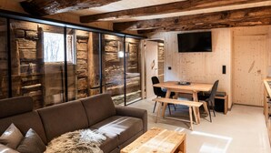 Ein modernes Interieur mit einem Holzesstisch, einer Couch und einem an der Wand befestigten Fernseher.