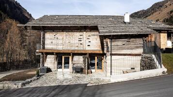 Ein rustikales Holzhaus mit steinernen Fundamenten, einer Holzveranda und einem Metalltor.