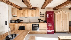 Eine Küche mit Holzschränken, einem roten Kühlschrank, einem Herd und einem Essbereich mit Tisch und Stühlen.