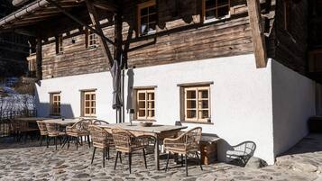 Un edificio rústico de madera con un patio empedrado de piedra y mobiliario de mimbre.