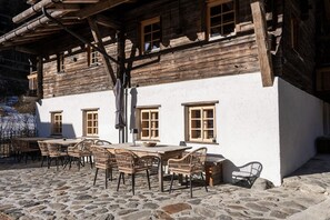En rustik træbygning med en patio anlagt med brosten og fletningsmøbler.