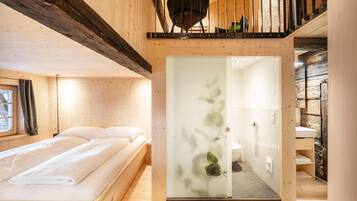 Ein Holzinnenraum mit einem Bett, einem Badezimmer und einer Treppe.