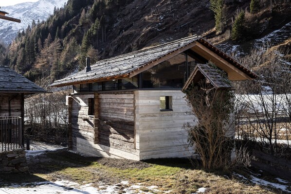 A rustic wooden cabin with a sloped roof, a small balcony, and a stone foundation.
