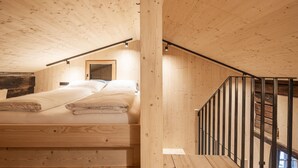 Ein Holzinterieur mit einem Bett, einer Treppe und Blick nach draußen.