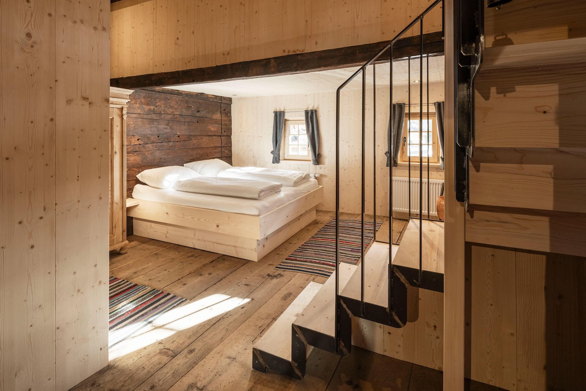 Um interior de madeira com uma cama, escada e janela.