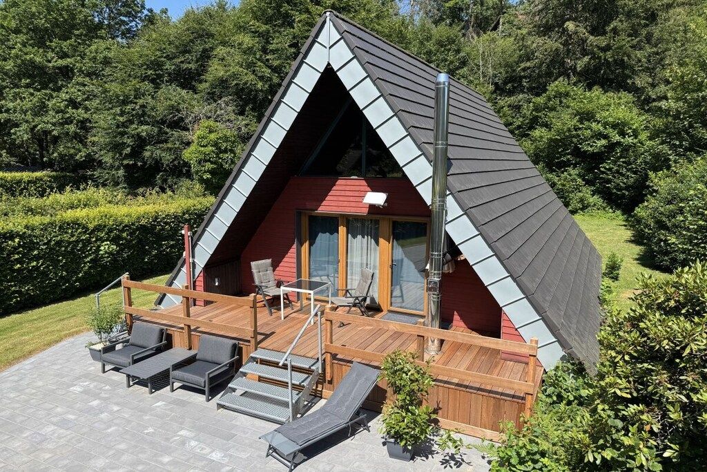 Un bâtiment de forme triangulaire doté d’une terrasse en bois, de sièges extérieurs et d’un escalier menant à l’entrée.
