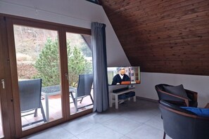A room with a television, a bench, and a view of the outdoors. - Holiday home with 1 bedroom (Simmerath)
